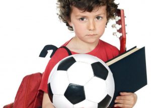 boy holding ball, book, backpack, guitar
