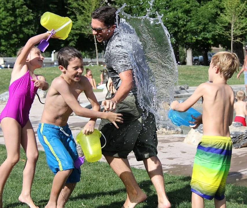 kids and grownup having water fight