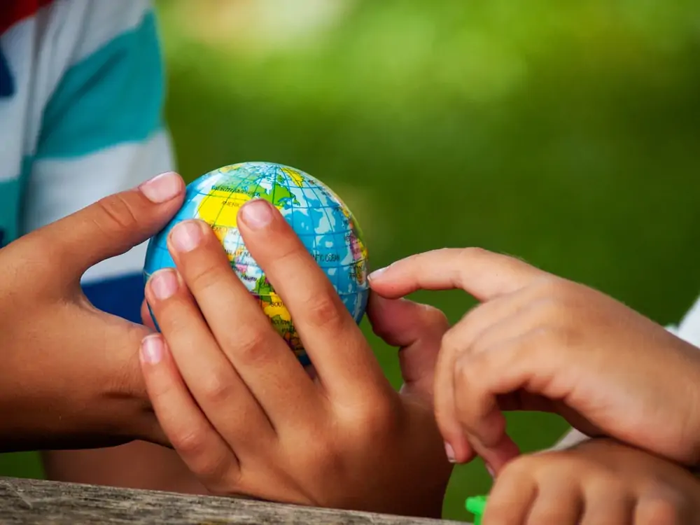 children's hands holding Earth model