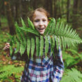 girl holding fern frond up to her chin