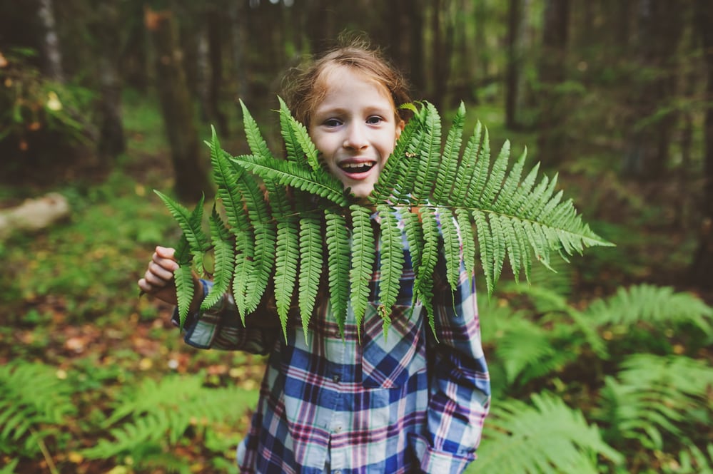 girl holding fern frond up to her chin