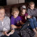 kids on couch ignoring each other using mobile devices