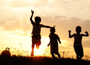 kids in silhouette playing in meadow