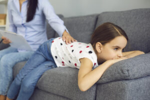 girl face down on couch ignoring adult